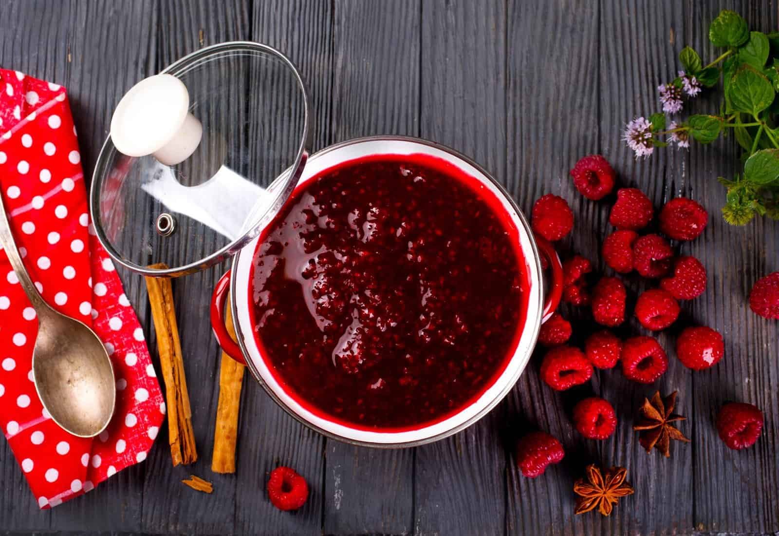 a pot of raspberry jam with a lid and berries
