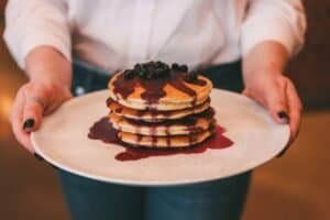 Pannkakor med blåbär och bärsås serverade på vit tallrik